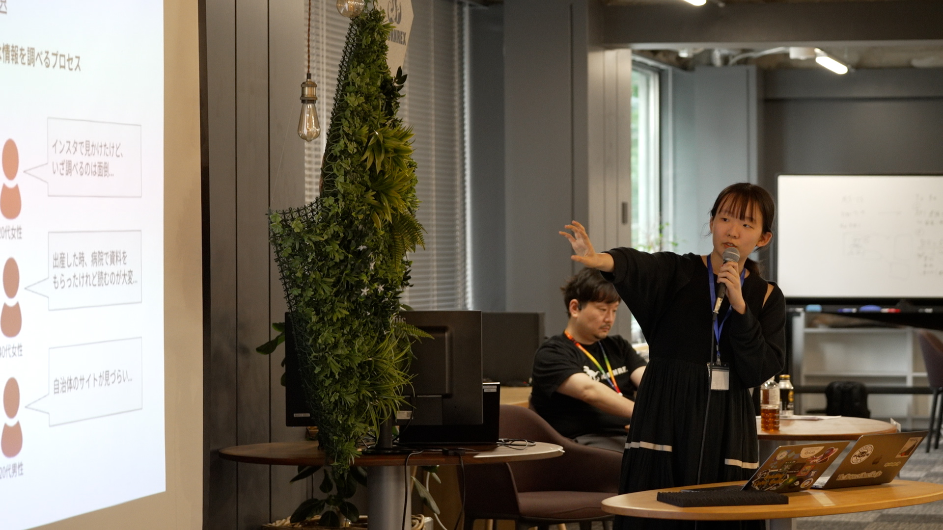 Participants at a hackathon. A woman projects material on a monitor and makes a presentation.