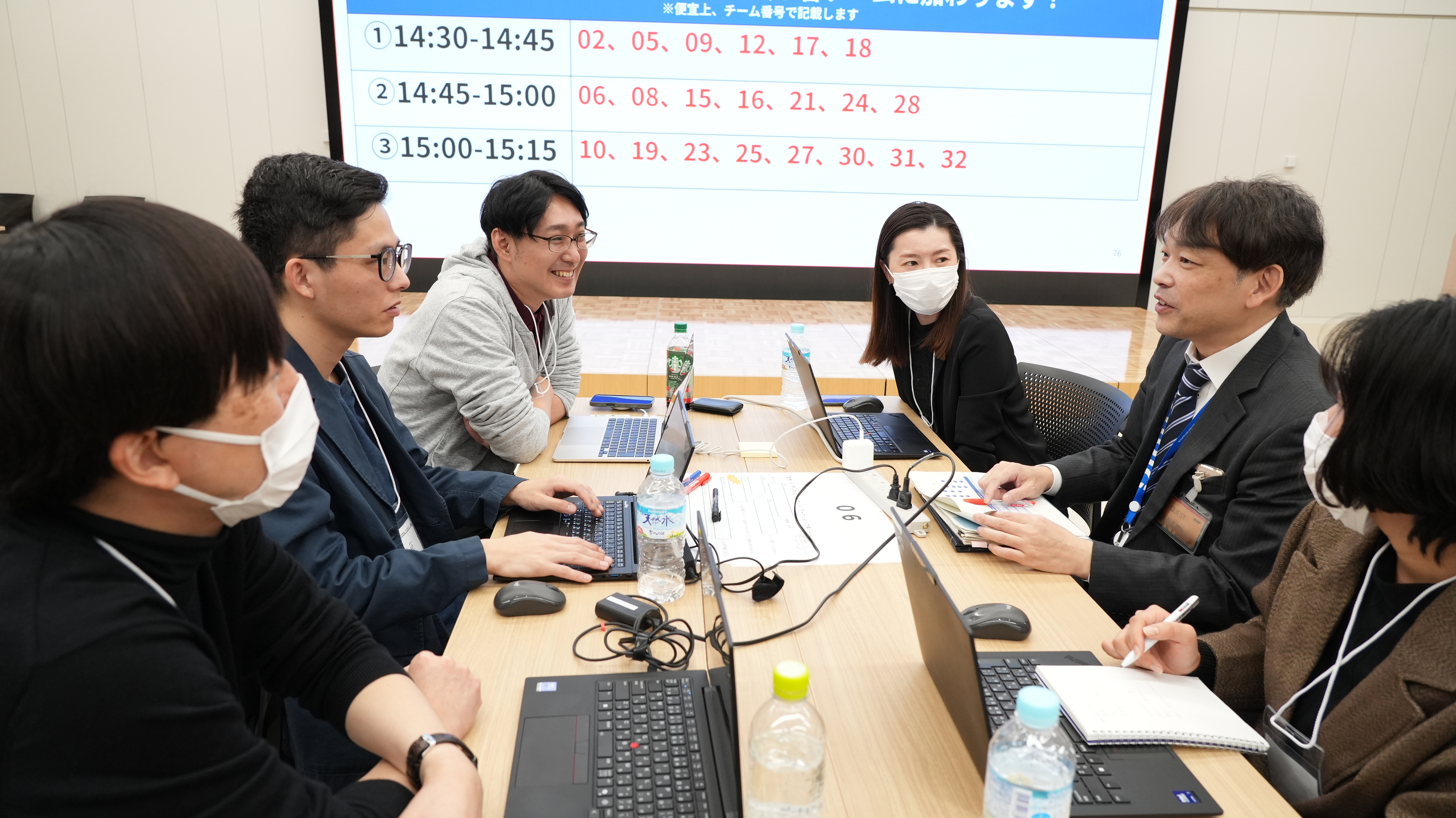 Digital Agency officials sit at a table with hackathon attendees and discuss ideas for the works they will develop. 