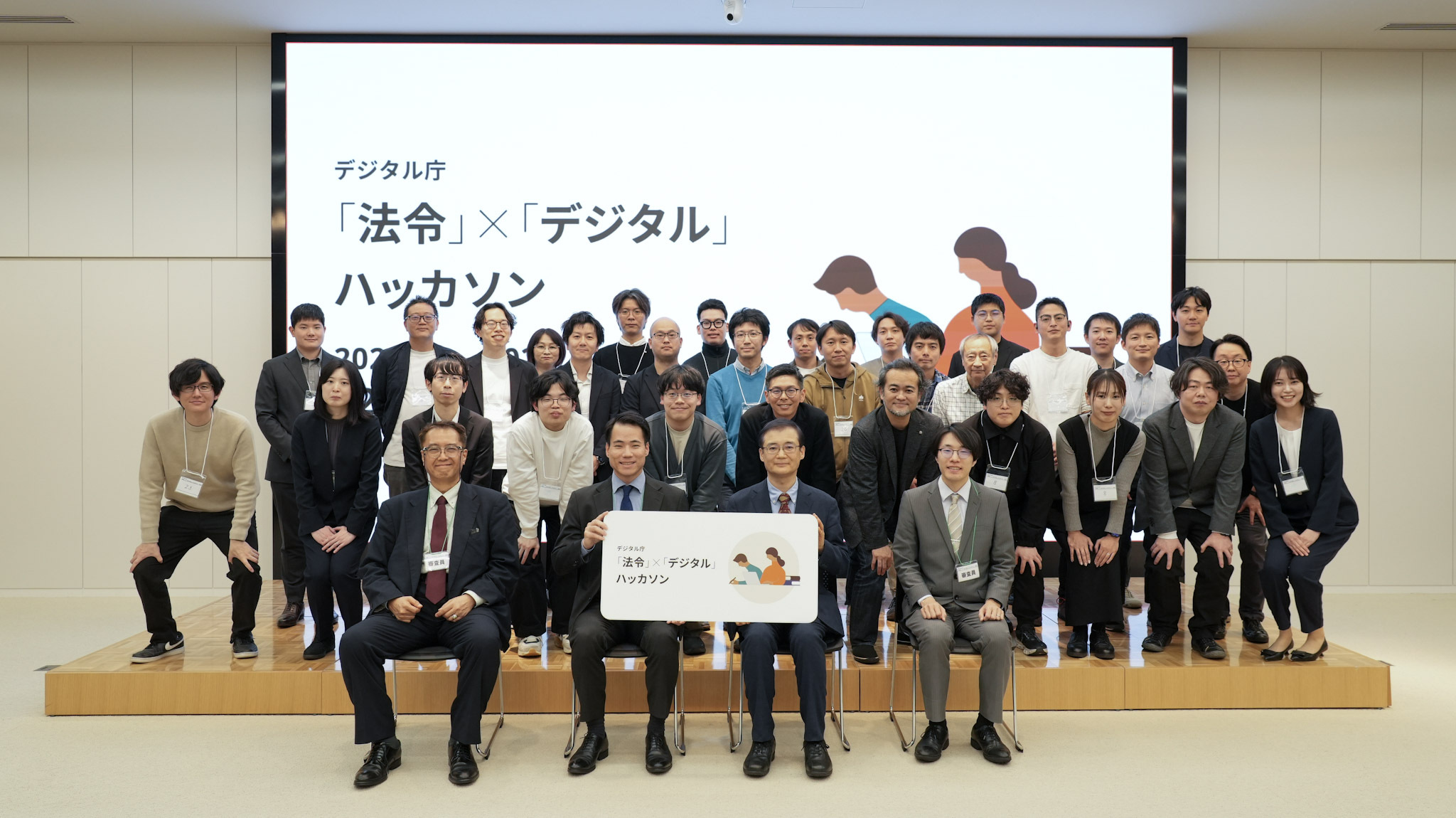 Group photo of four judges and hackathon participants. Four judges are seated in the front row, and two judges in the center hold a board that says "laws and regulations" x "Digital" hackathon. 