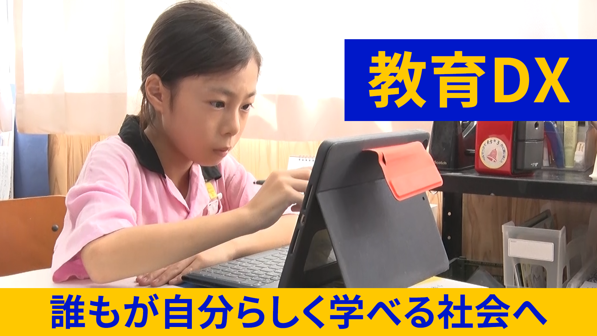 小学校の教室の自席で、タブレット端末の画面を見ながら操作する小学生の女の子の画像