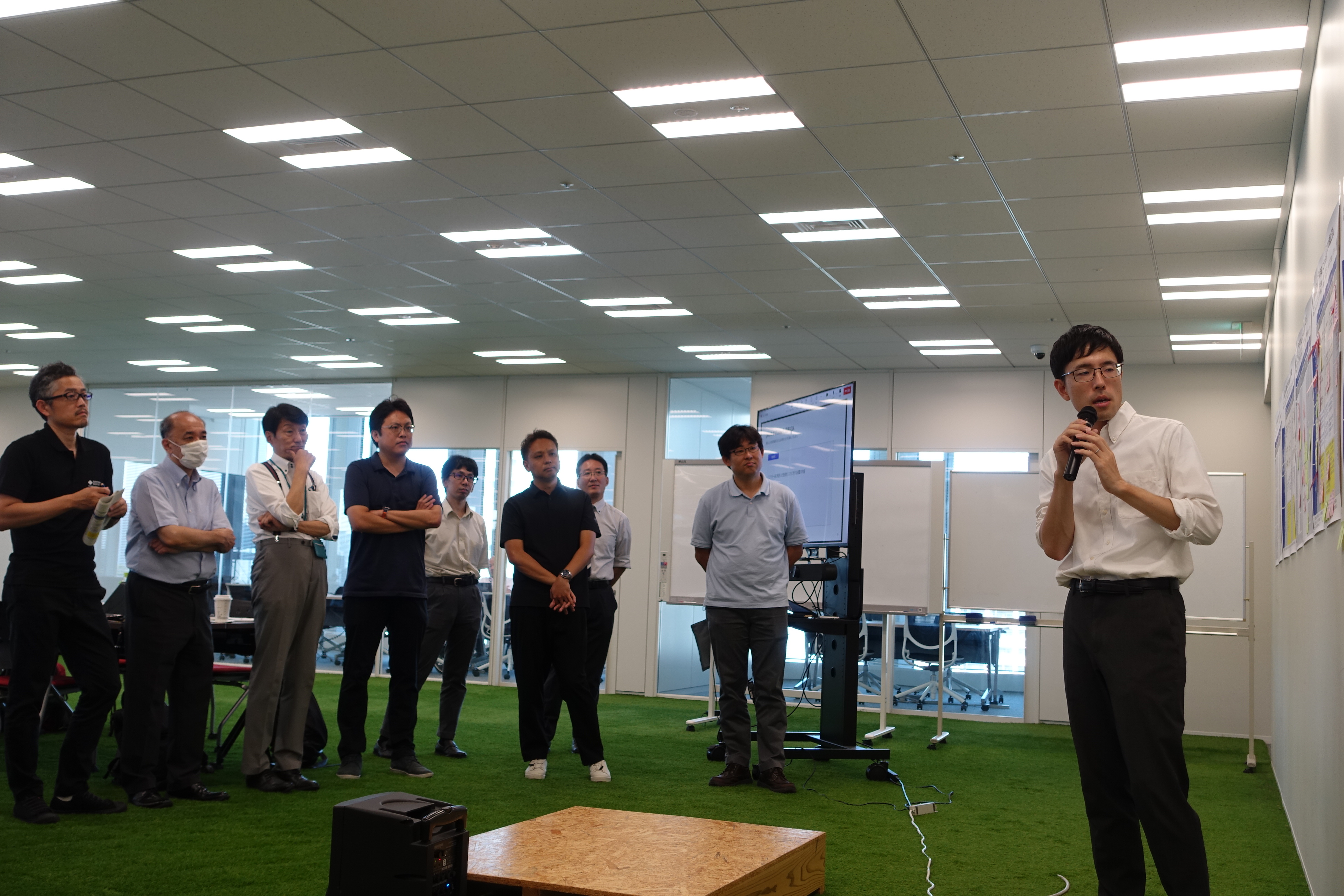 写真右側に北山弁護士が写っており、立ちながらマイクを持って壁に貼られた紙を見ながら話している。写真中央から左にかけて参加者が写っており、立ちながら話を聞いている。