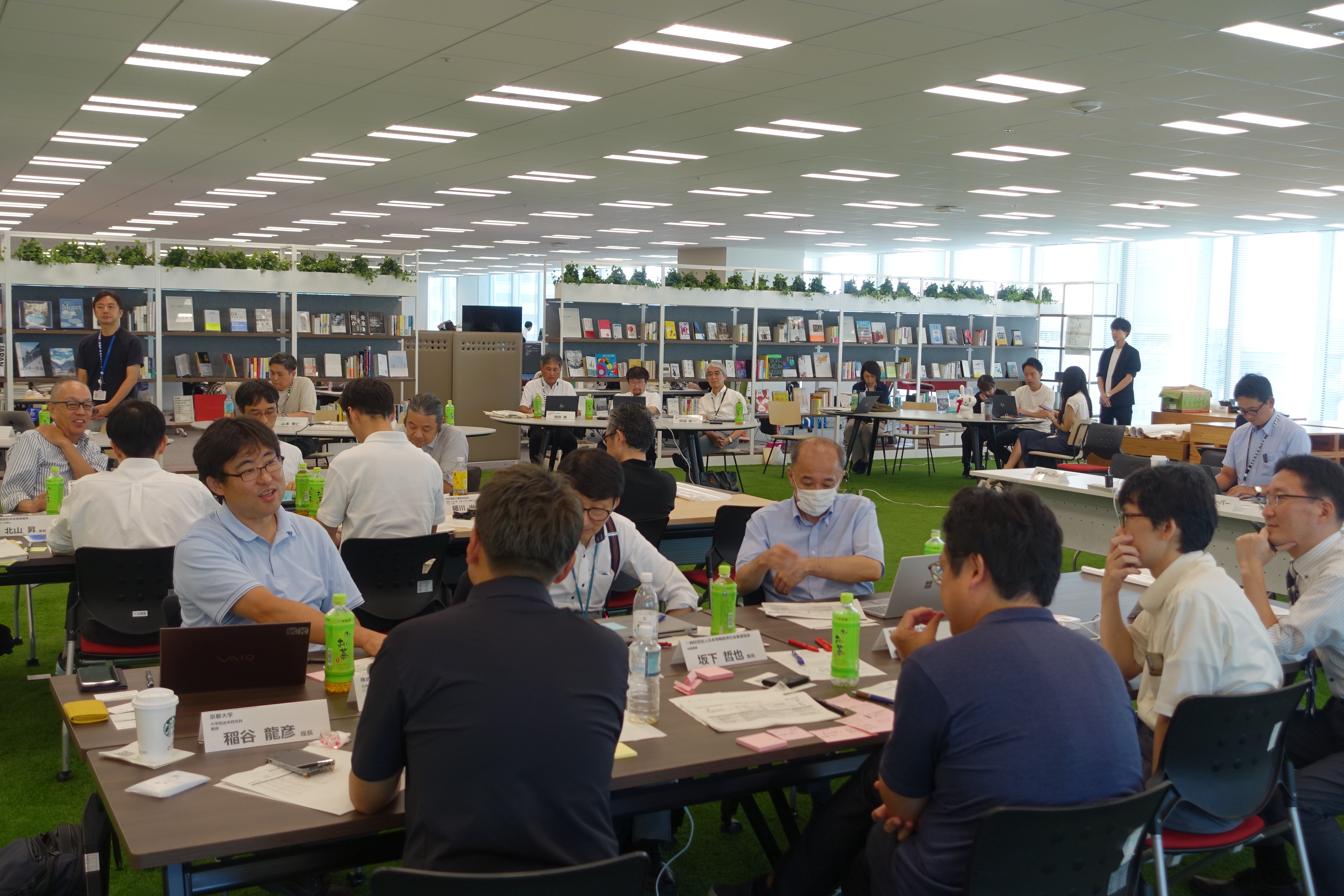 有識者が2つのチームに分かれて座り、付箋等を使いながら真剣な面持ちで議論をしている写真