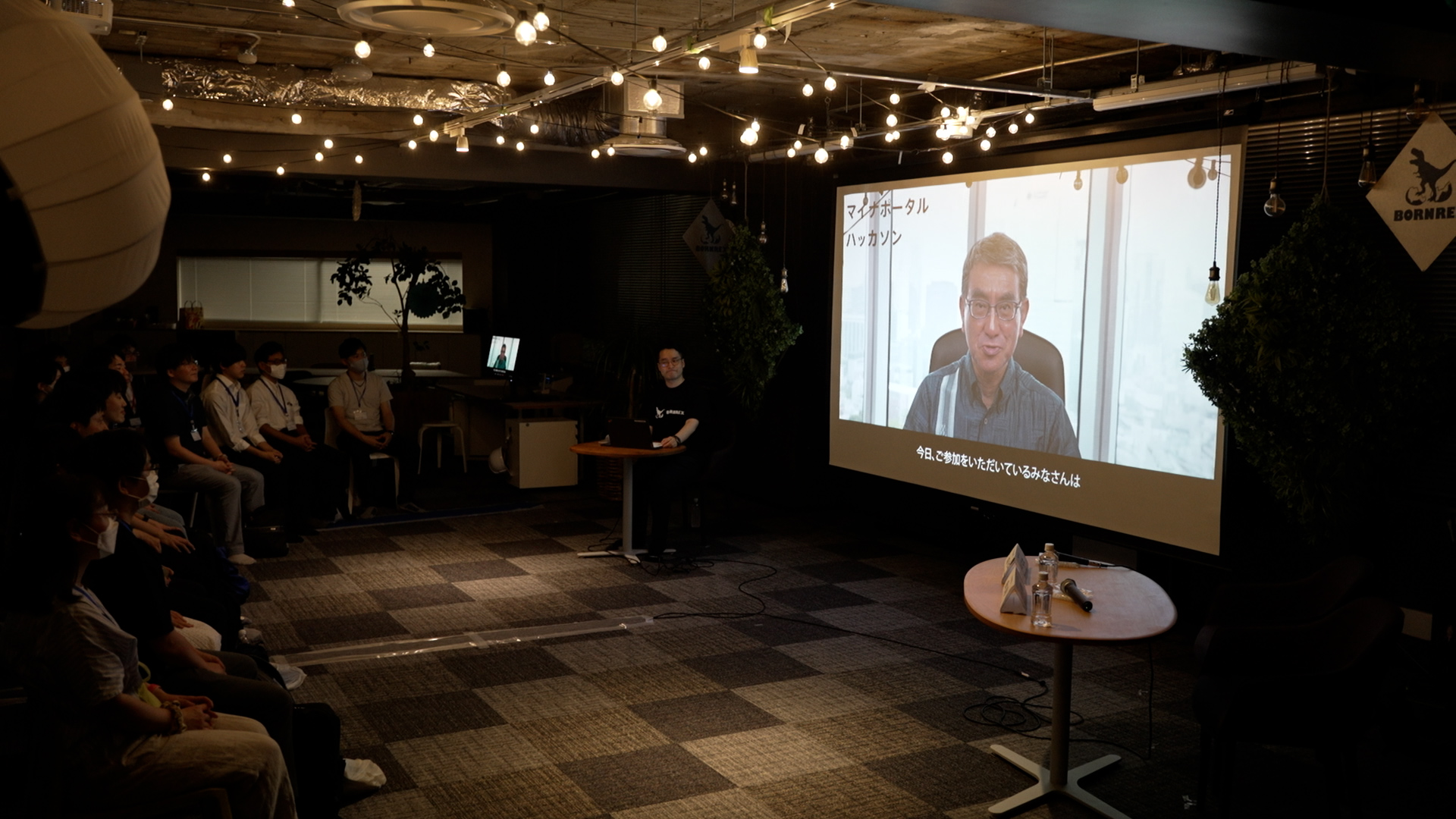 A video of the Minister's opening address is shown on a monitor.