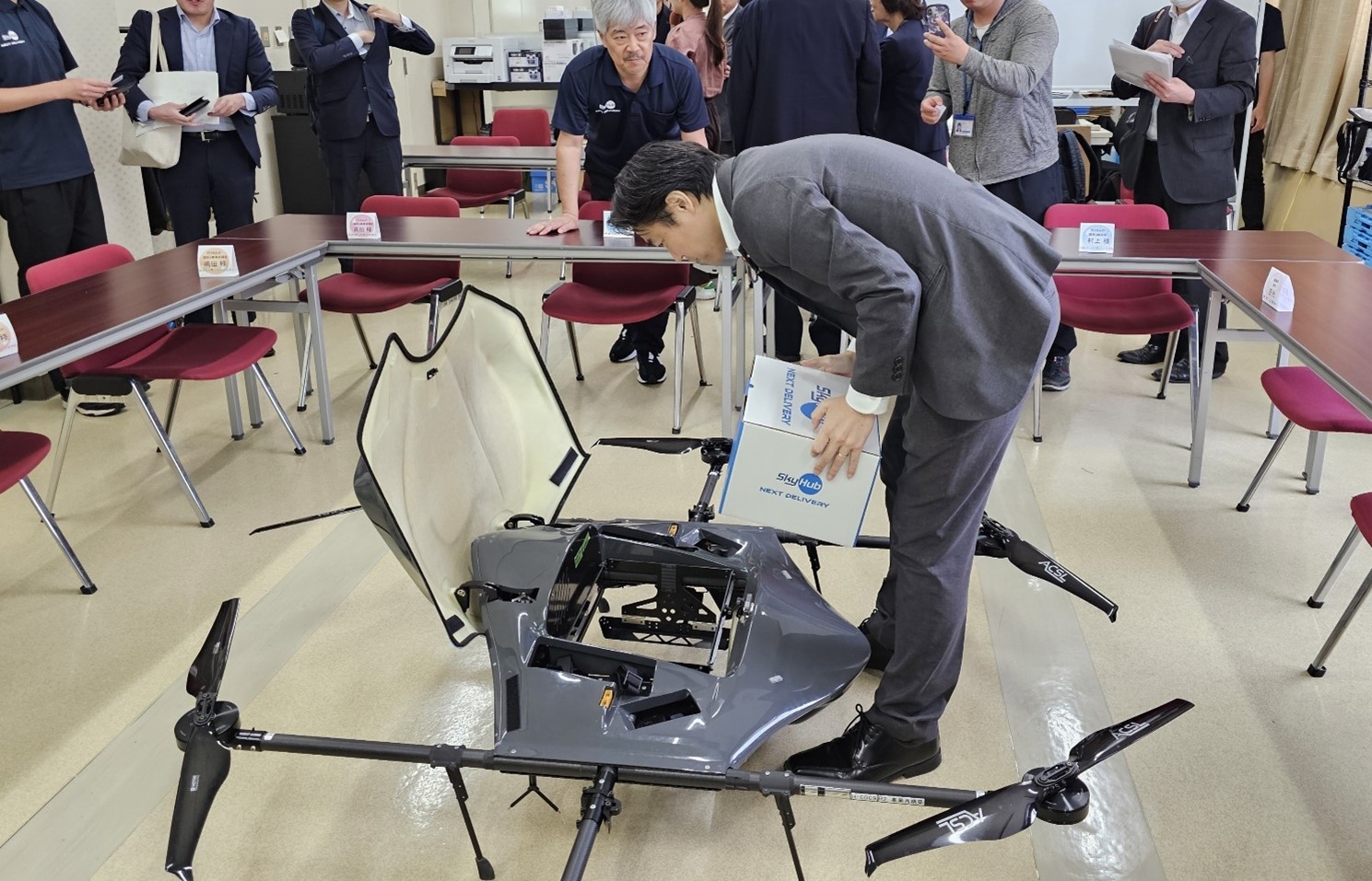 ドローンの前に穂坂副大臣が屈みながらドローンの仕組みを見ている写真。