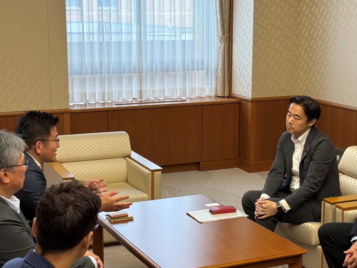 穂坂副大臣と石川県浅野副知事が椅子に座って面会をしており、石川県浅野副知事が穂坂副大臣に説明している写真。