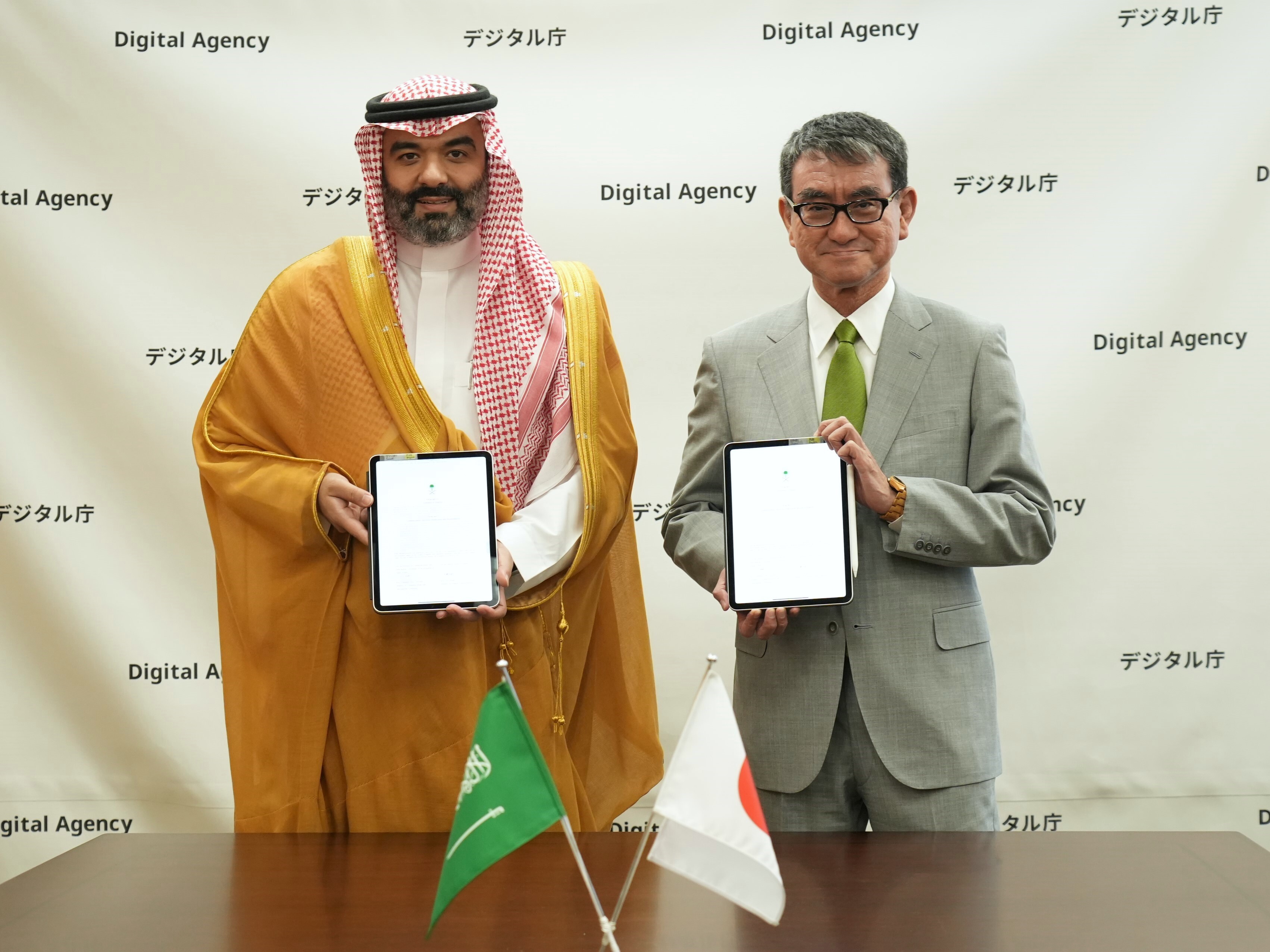 署名したタブレットを持つ河野大臣とアッブドラー・ビン・アーメル・アル＝スワーハ通信・情報技術大臣
