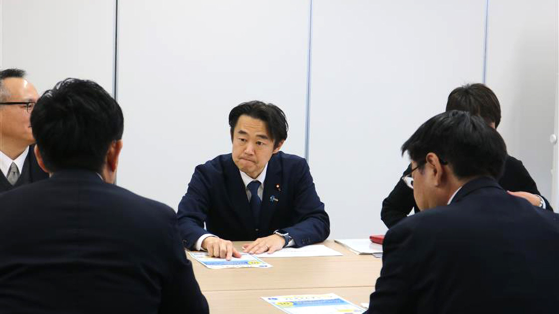 穂坂デジタル副大臣と商工会職員が着席し、商工会職員からあさひまちコインについて説明を受ける様子
