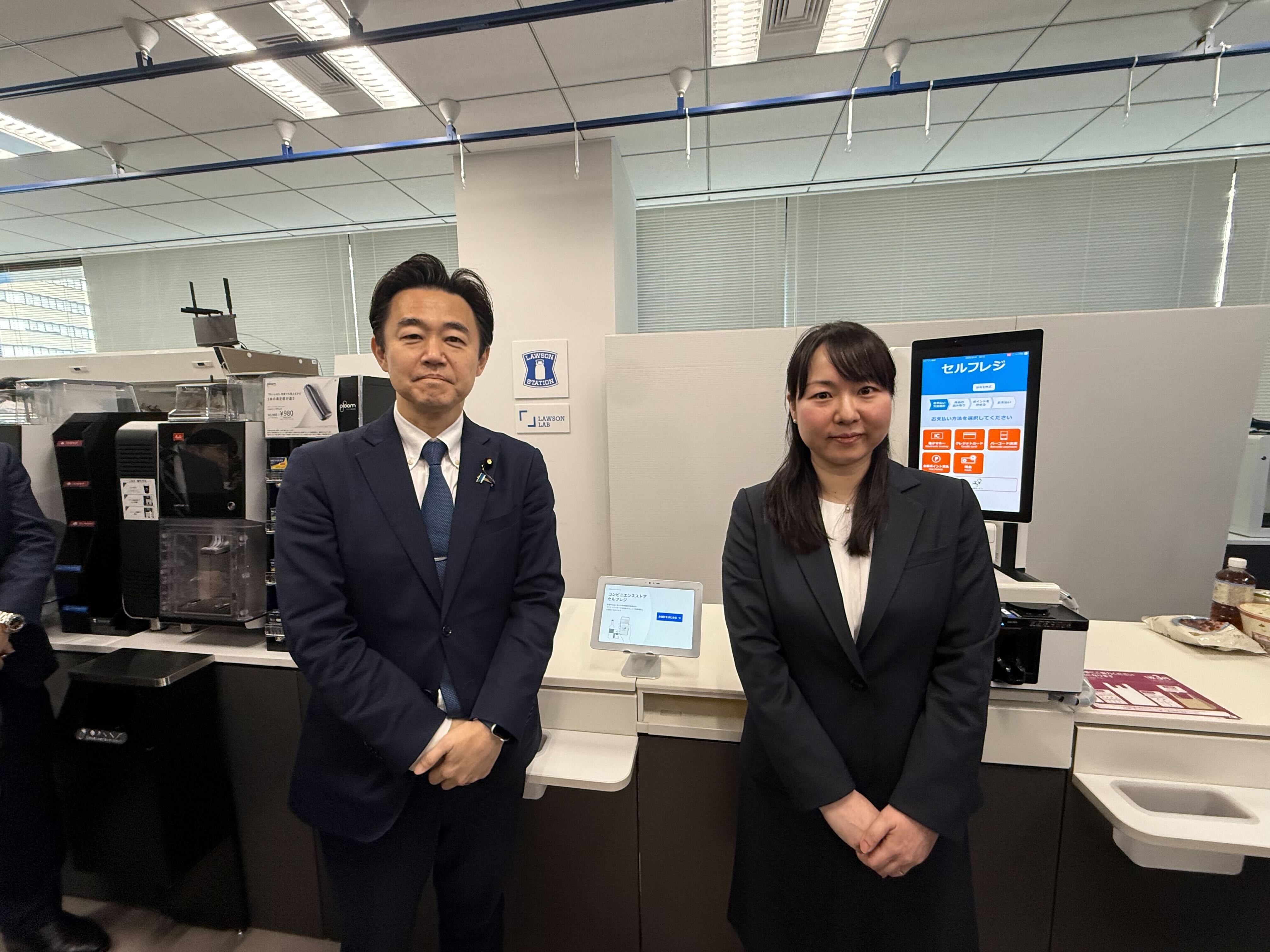 With the checkout counters of retail stores in the background, Mr. Hosaka, State Minister for Digital Transformation, on the left and Kasai, chairman of the Japan Franchise Association's Study Group on Digital Certification for Age Verification of Alcohol and Tobacco, on the right stand side by side.