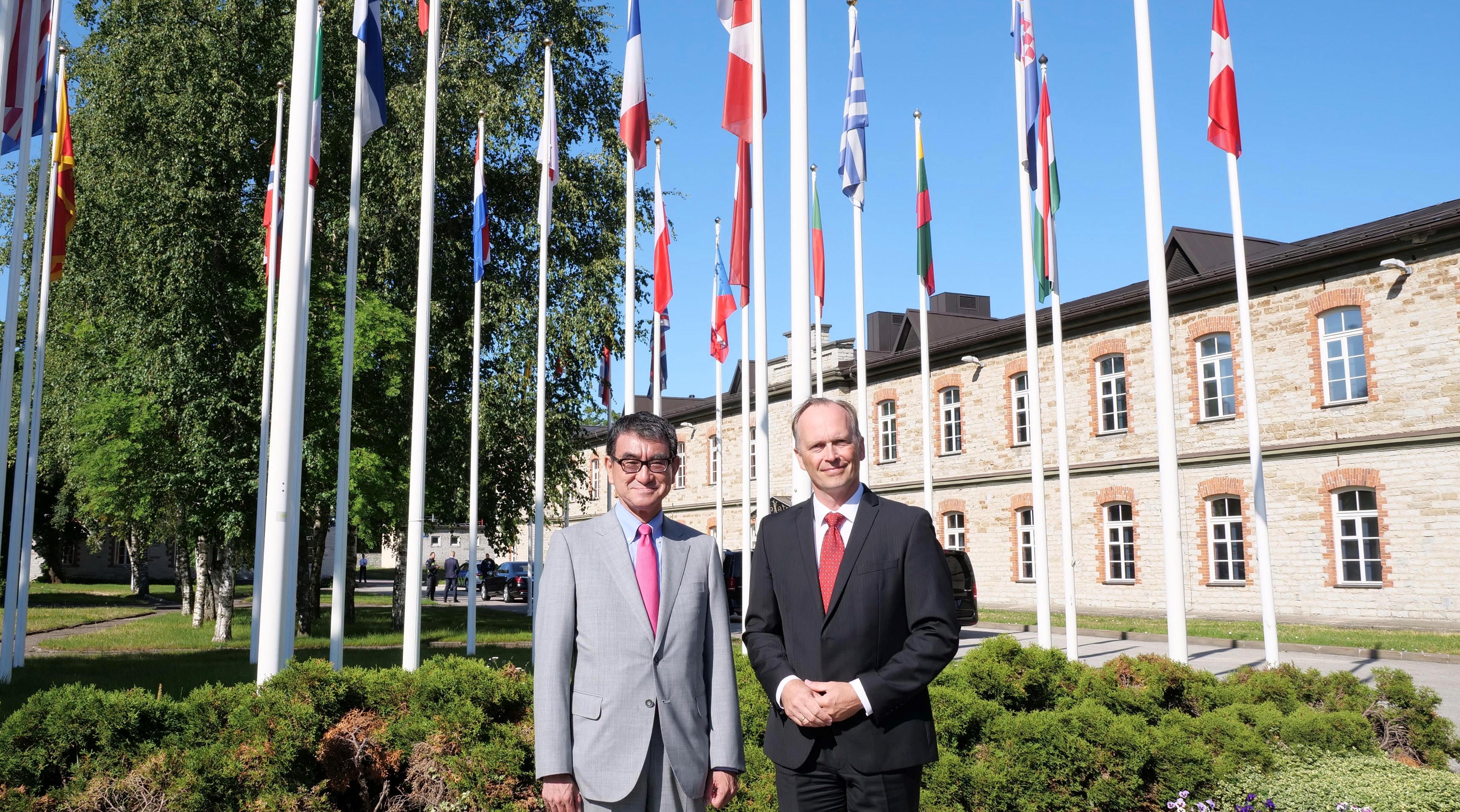 Photo of Minister Kono (right) standing in front of the Cooperative Cyber Defense Center of Excellence.