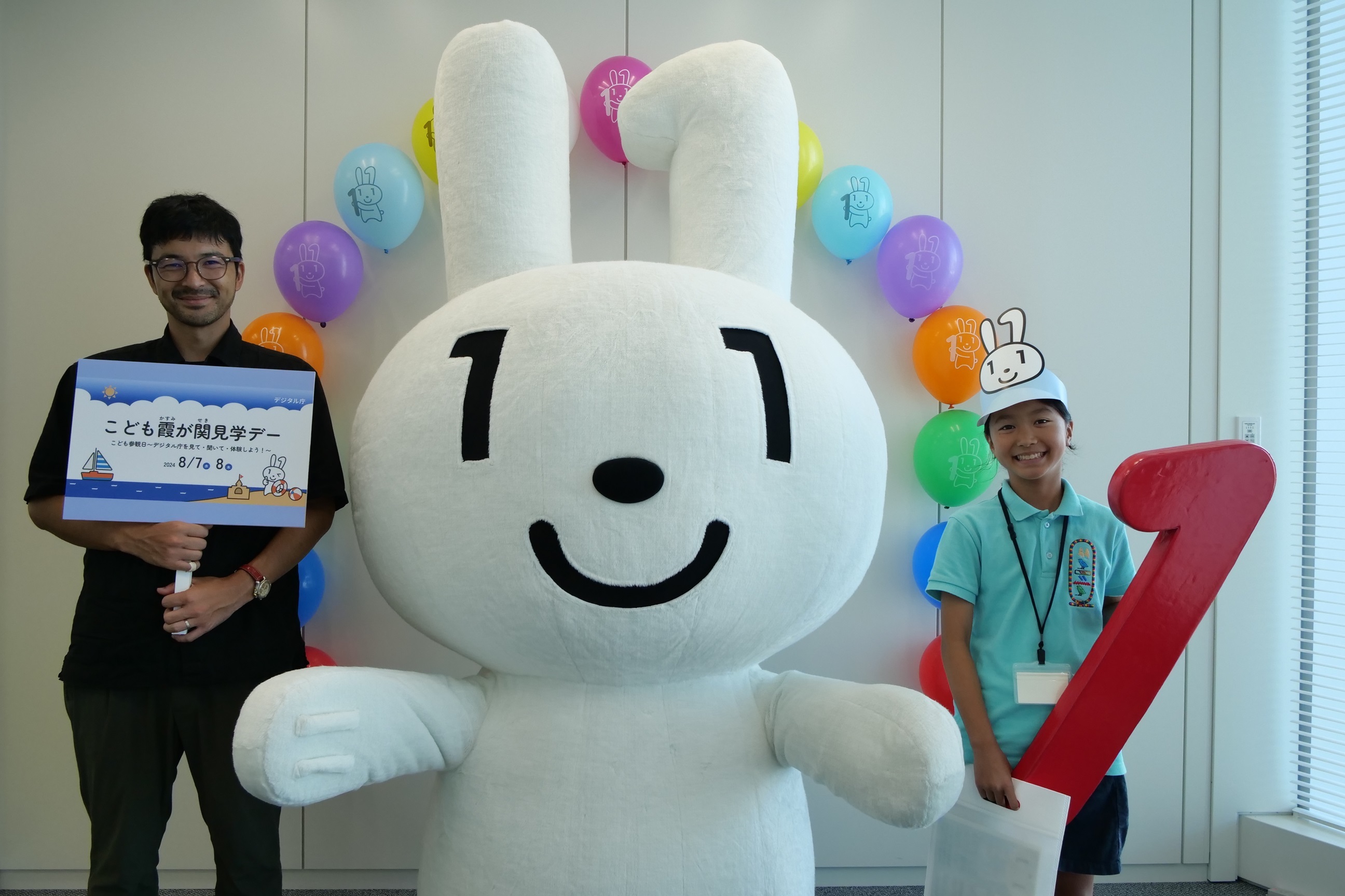 Dependents and parents pose for a photo with their Maina-chan