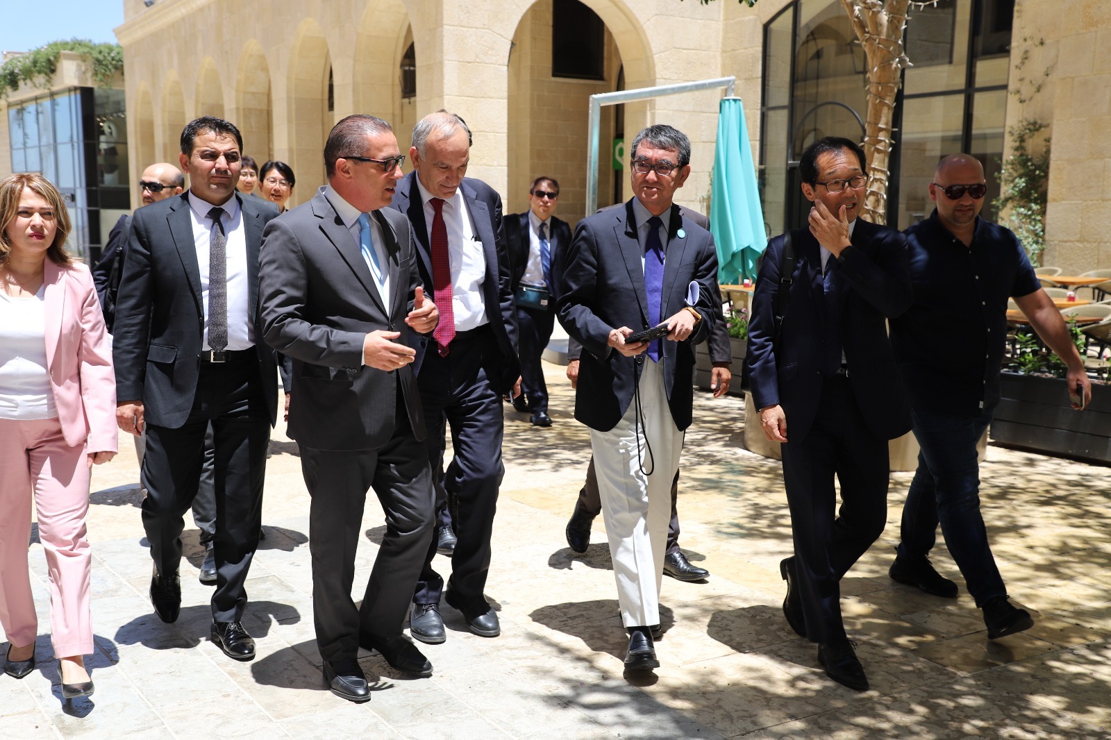Photo of Minister Kono visiting the Palestinian Territories. He is receiving an explanation from Minister Sadr while walking.
