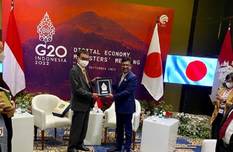 Two shots of Minister Kono standing with Indonesian Minister of Information and Communications Pratae as they both hold what appears to be a shield.
