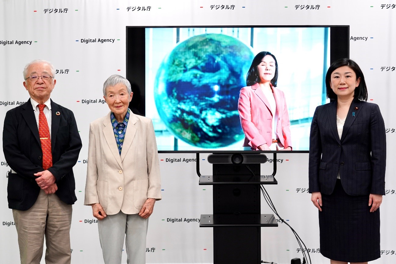 左から、牧壮さん、若宮正子さん、浅川智恵子さん、牧島かれんデジタル大臣が立って並んでいる。そのうち浅川智恵子さんはモニターに写し出されている。