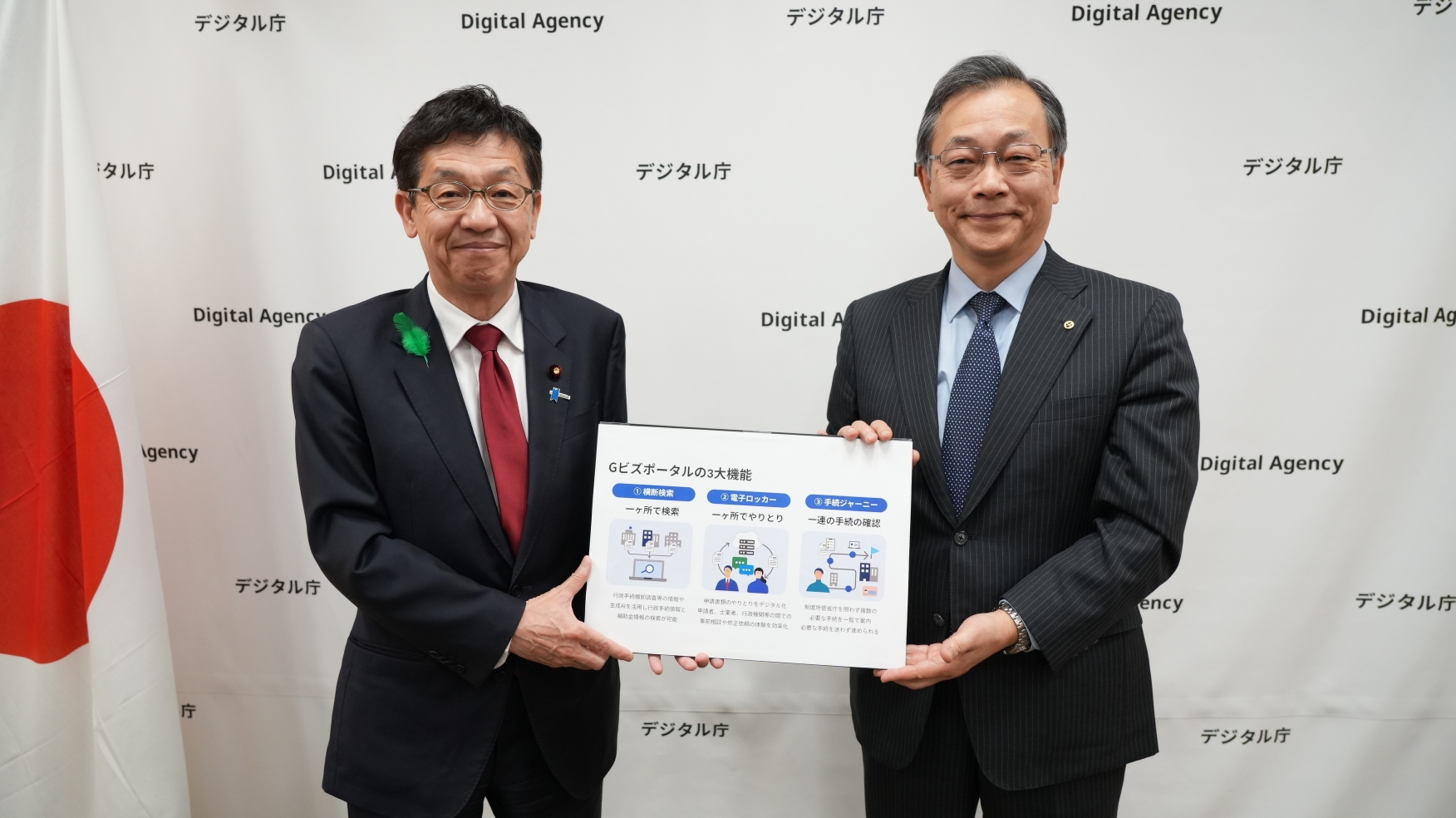 松本デジタル大臣と日本商工会議所 伊藤仁 専務理事の写真。左に松本デジタル大臣、右に日本商工会議所 伊藤仁 専務理事が立っており、二人が「Gビズポータル」についての1枚のフリップを持っている。