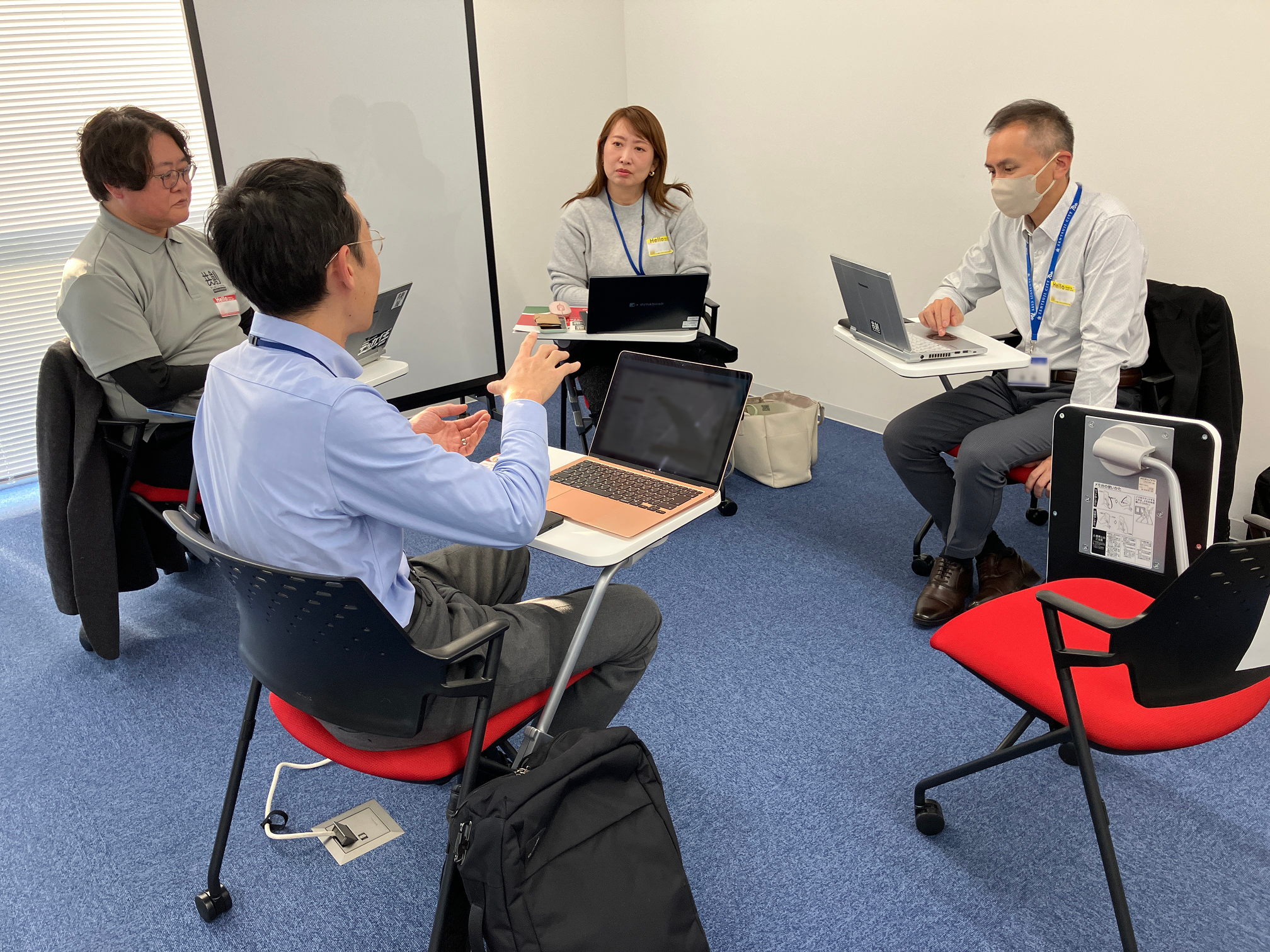 椅子を向かい合わせて4名が座っており、話し合っている写真。4名全員がパソコンを開いており、数名はパソコン画面を見つつ話し合っている。