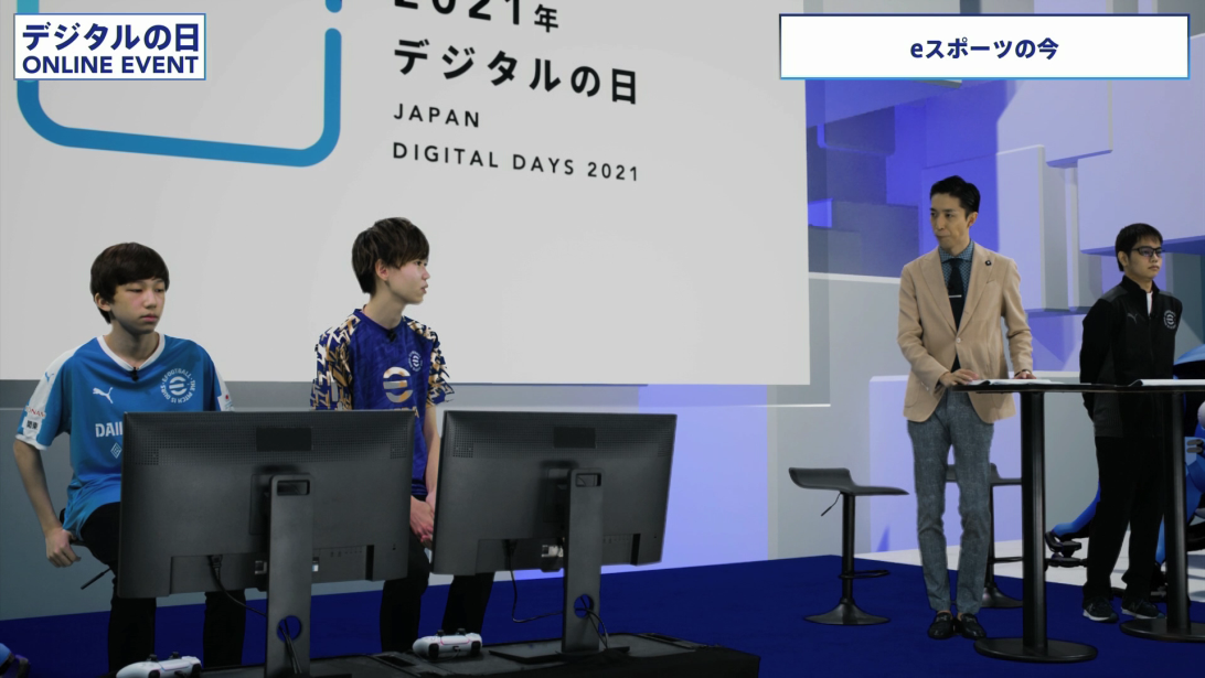 This photo shows an exhibition match of a competition title by an e-sports player. Tomoki Iimura and Hidekoya Kida are playing.