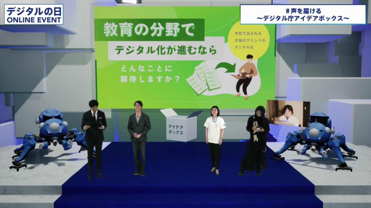 From the left, Mr. Takeshi Natsuno, Minister Makishima, and Mr. Yoichi Ochiai are standing side by side. To the right of them, a video of Mr. Hiroyuki Nishimura participating remotely is shown. In the background, an image of the topic, 