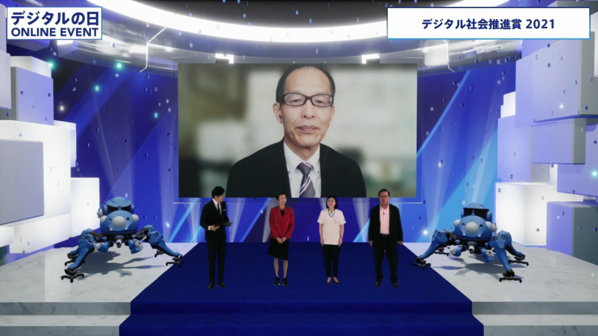 デジタル社会推進賞2021の発表の様子を映した写真。左から石倉洋子デジタル監、牧島大臣、村井純さんが並んで立っている。