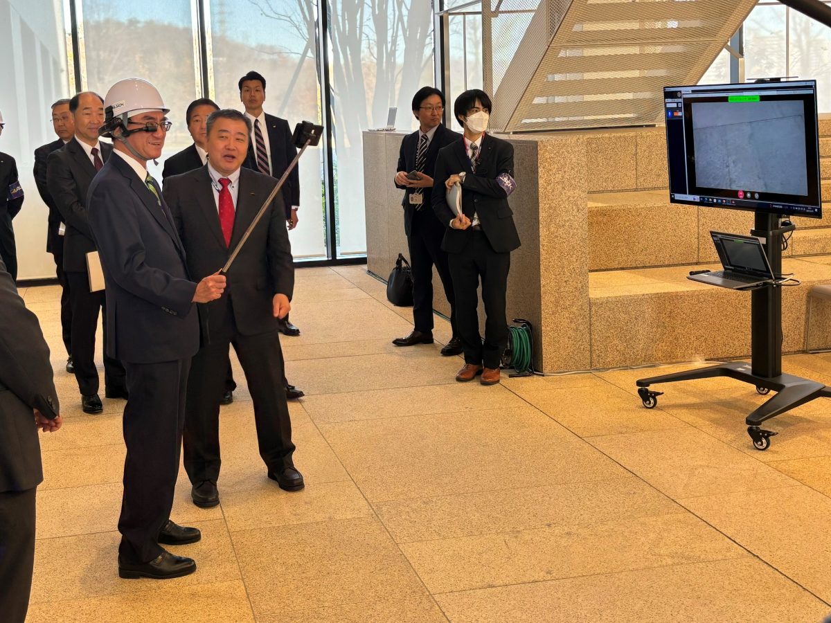 A Minister Kono wearing smart glasses and a staff member explaining the experiment