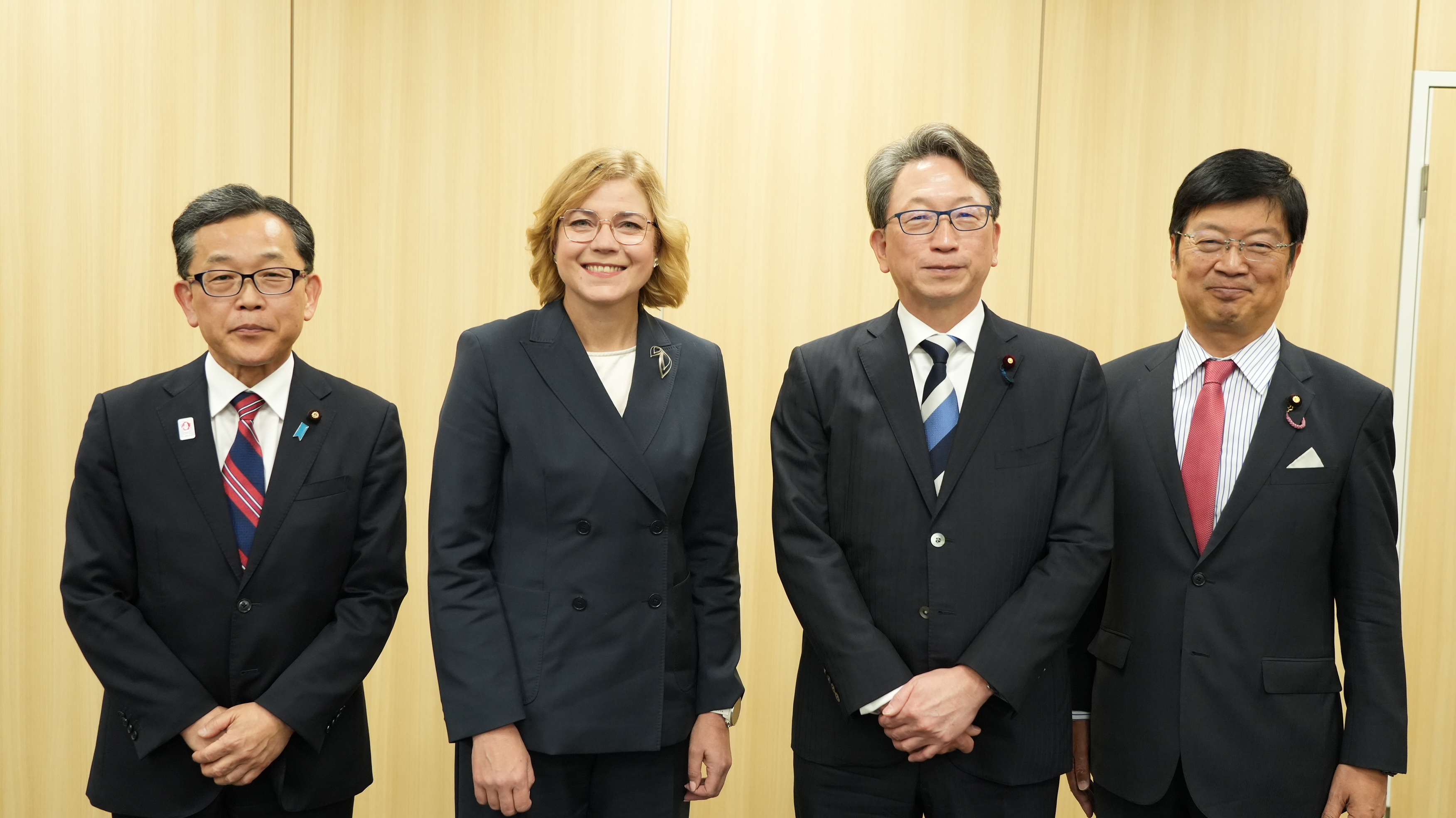 4人が壁の前で並んで立っている様子