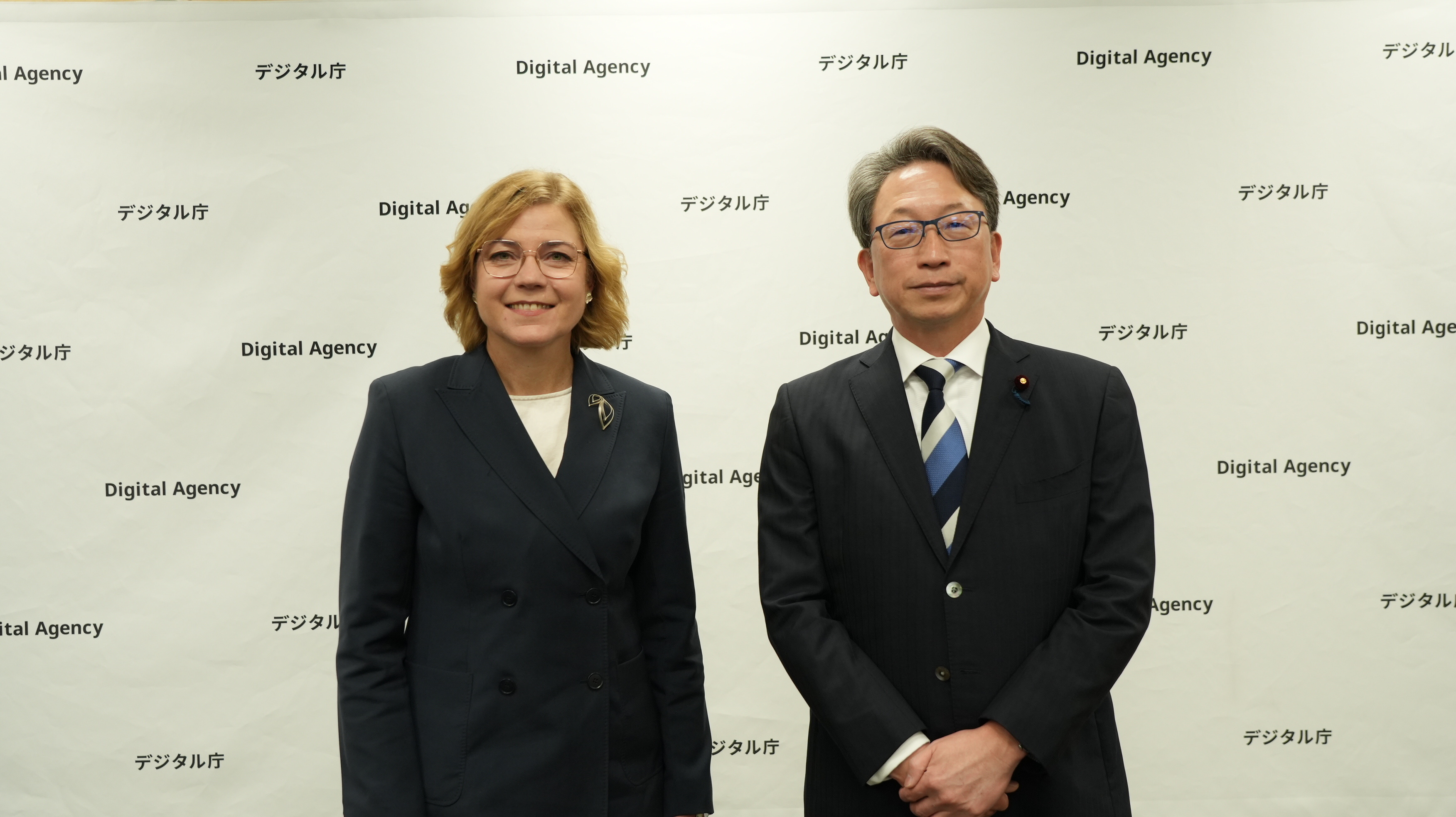 2人が壁の前で並んで立っている様子