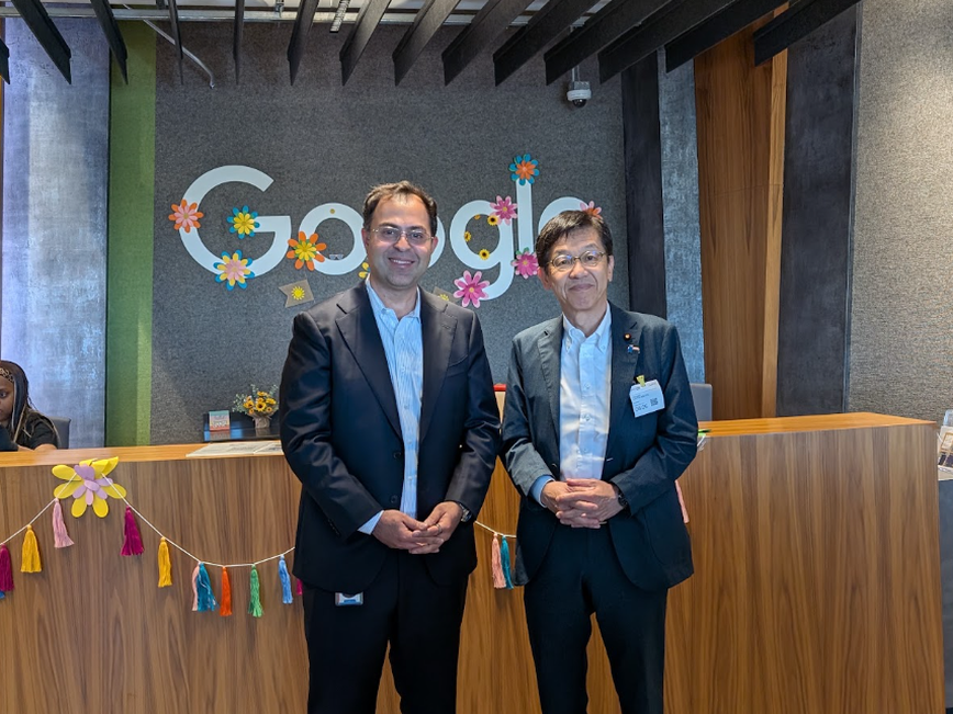 Googleと書かれた壁の前で、アンカー・メロートラ上級副社長と松本デジタル大臣が並んで立っている。