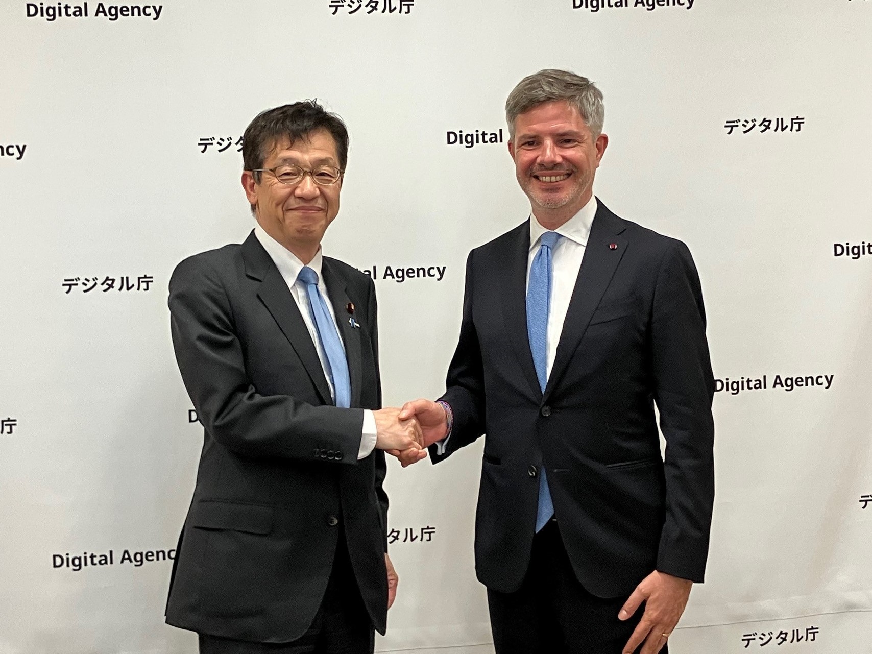 松本デジタル大臣とエヴラー駐日ベルギー大使の写真。左に松本デジタル大臣、右にエヴラー駐日ベルギー大使が立っており、二人が笑顔で握手をしている。
