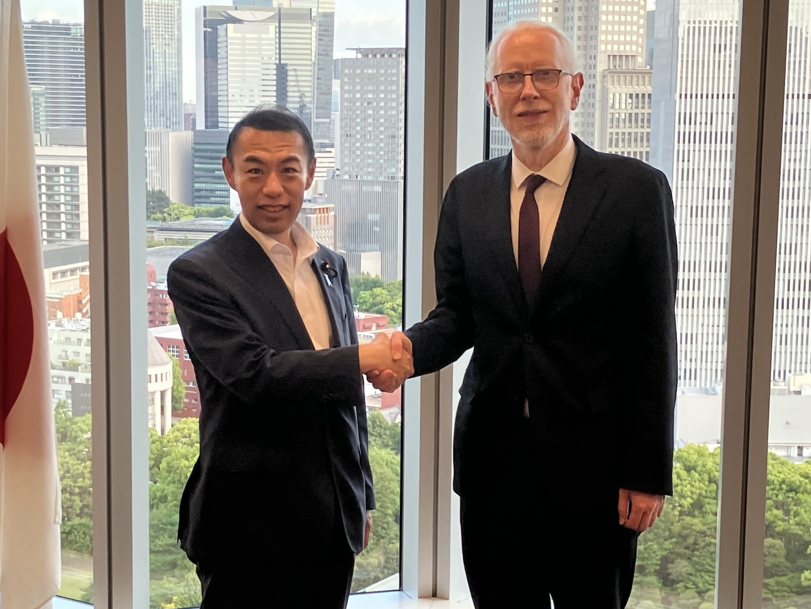 今枝副大臣（左）とコソボのヤグジウ デジタル化・公共行政大臣（右）が会談中に笑顔で握手している様子。