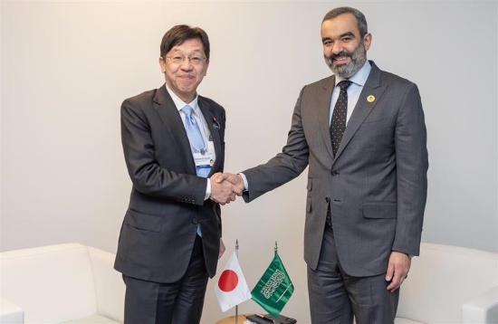 Minister Matsumoto (left) shaking hands and smiling with Minister of Communications and Information Technology of the Kingdom of Saudi Arabia, Eng. Abdullah bin Amer Al-Swaha (right)　with the flags of both countries at the center.