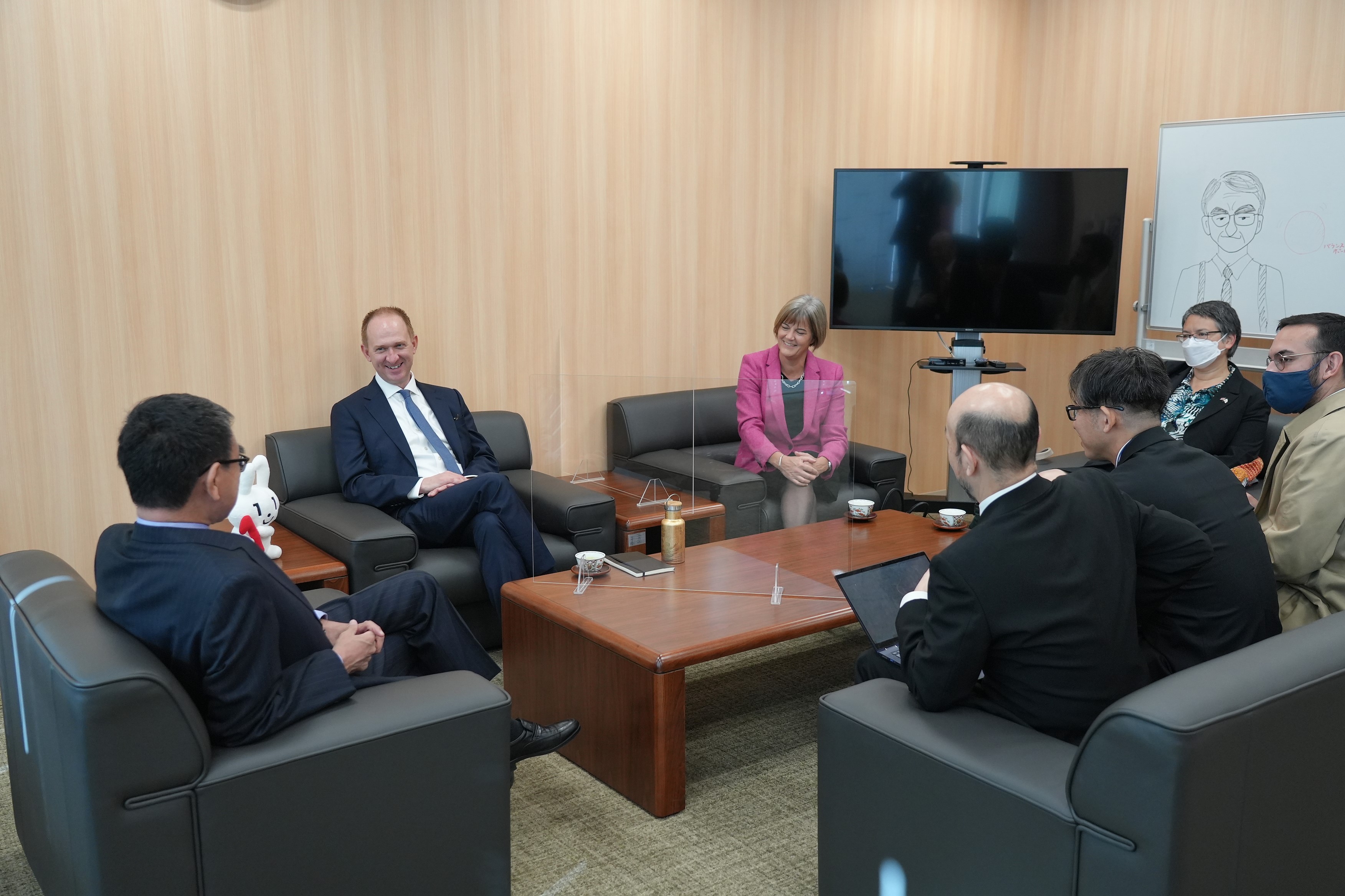 ジェレミー・クイン英国内閣府担当大臣兼主計長官、トム・リード英国GDS長官と河野太郎デジタル大臣達が机を囲み、椅子に座って話している風景。