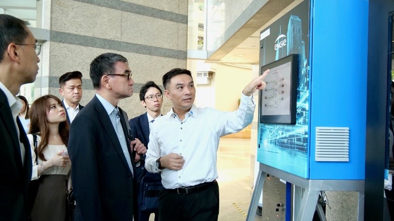 Photo of Minister Kono receiving an explanation of the system at Punggol Digital District.
