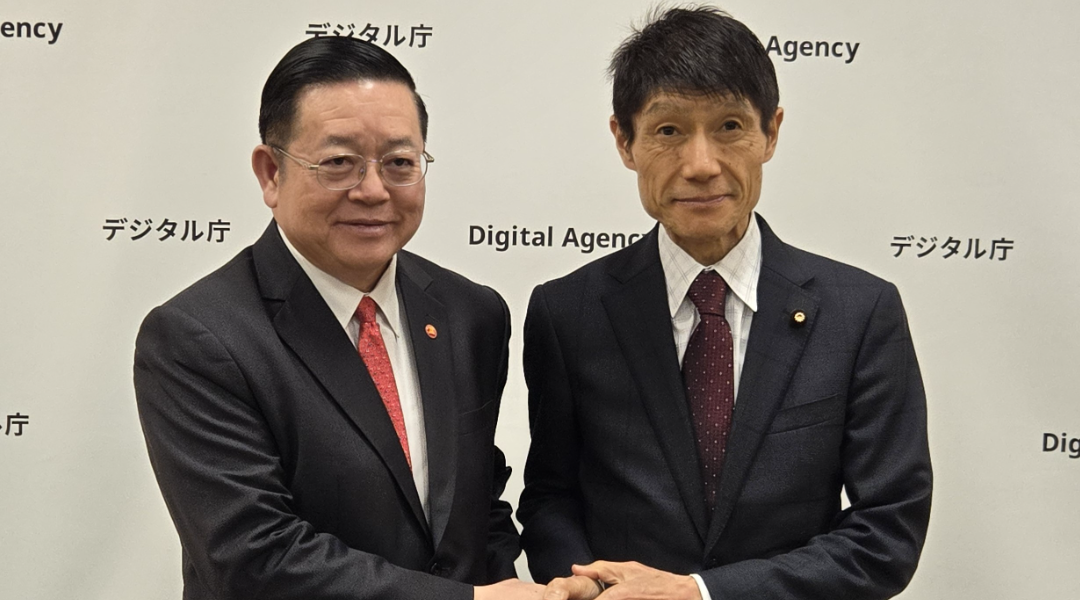 カオASEAN事務総長（左）と古川デジタル大臣（右）がデジタル庁のロゴパネルの前で握手を交わす様子。