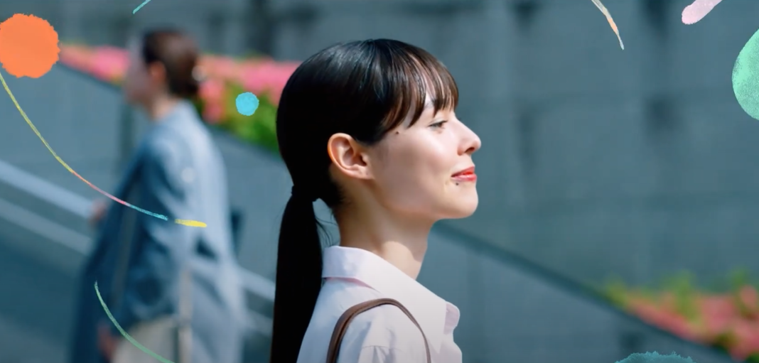 An image from one of the scenes in the video. The young woman at the beginning walks with a smile through the crowd.
