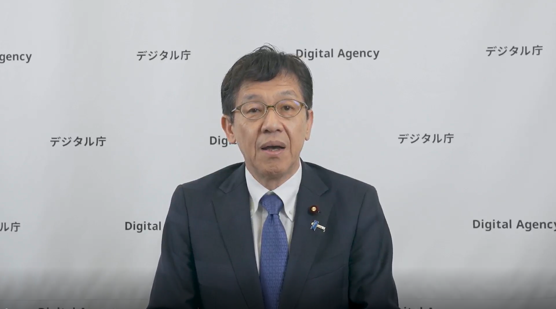 室内で、松本デジタル大臣がビデオメッセージを述べている様子。