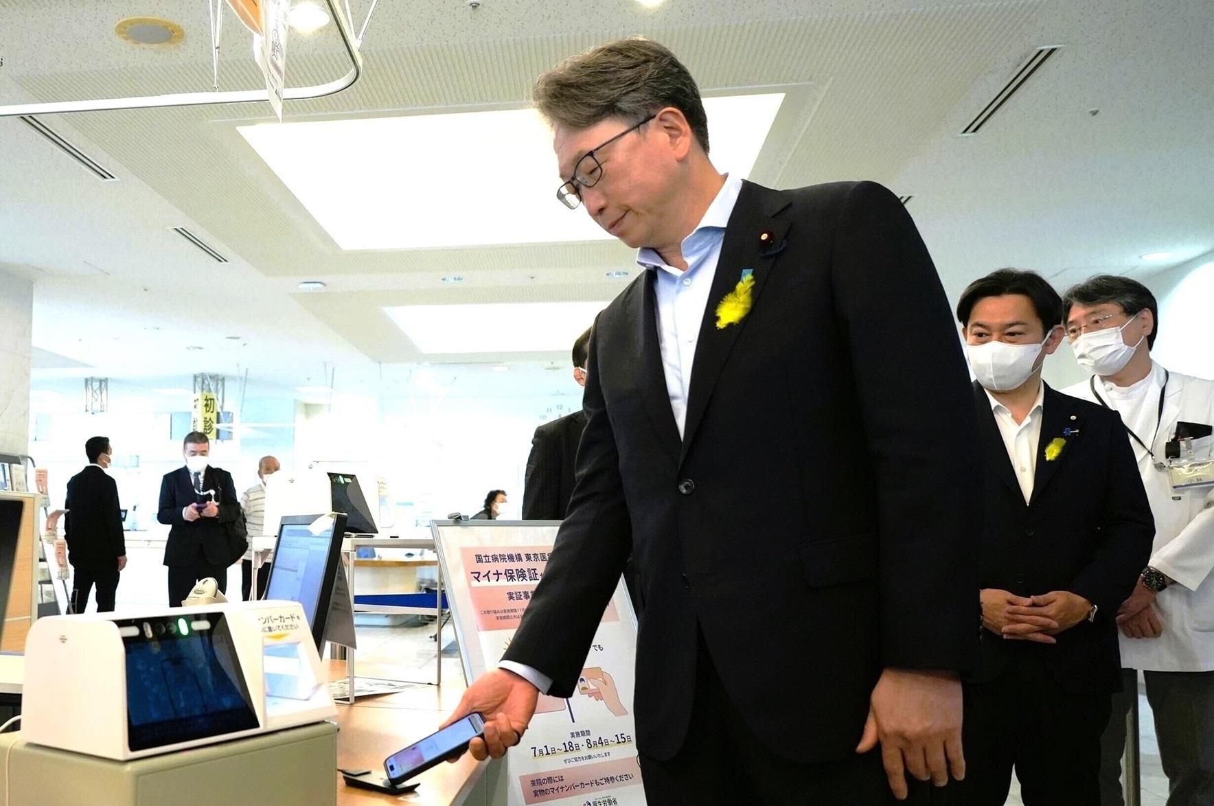 Photo during the inspection. Mr. Taira, Minister for Digital Transformation, is receiving at the My Number Card of the smartphone