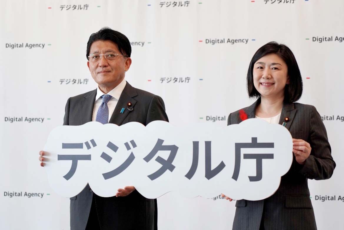 平井卓也前デジタル大臣と牧島かれん新デジタル大臣のツーショット。二人はデジタル庁のロゴを手に持っている。